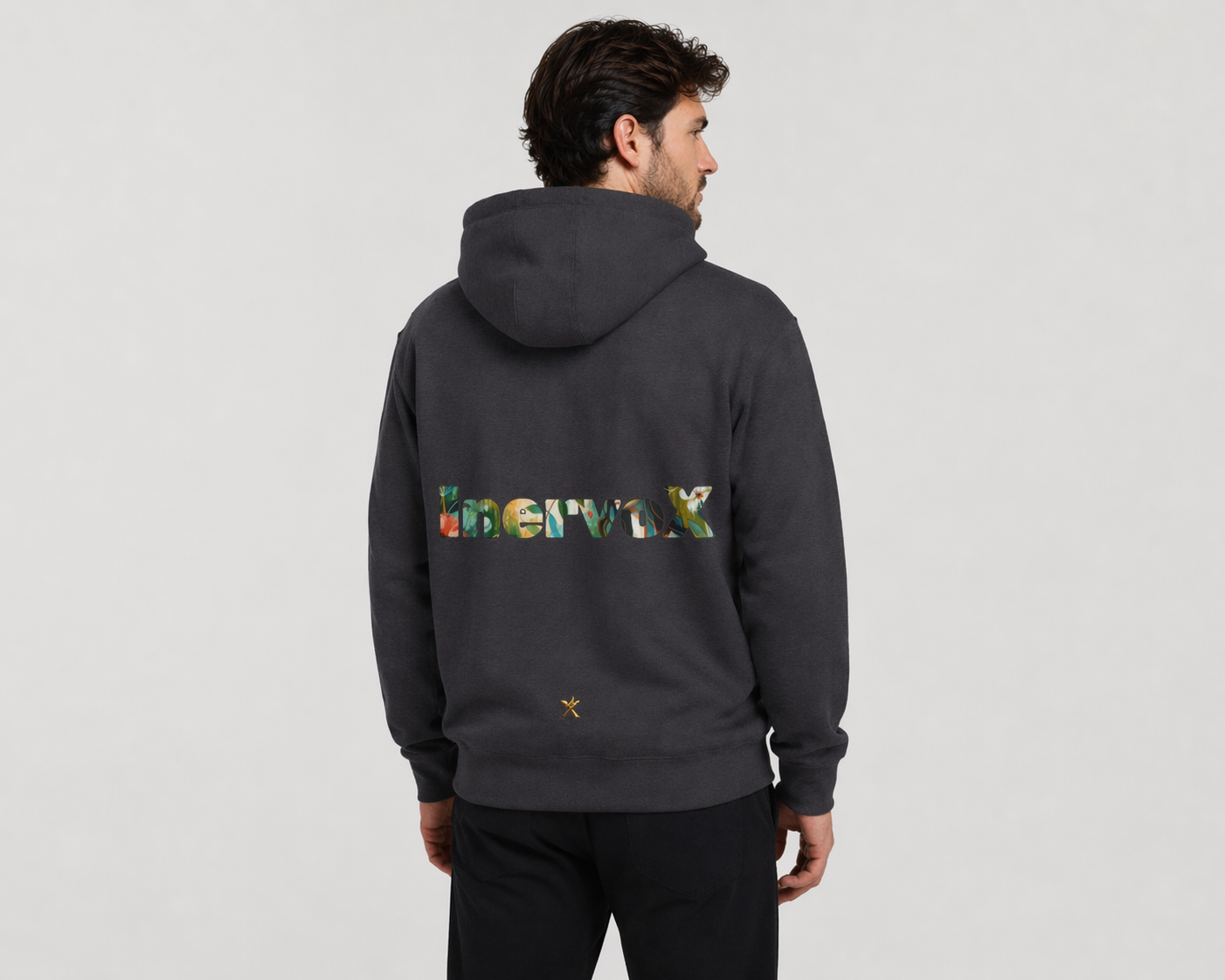 Man wearing a dark gray hoodie with colorful text on the back against a light gray background