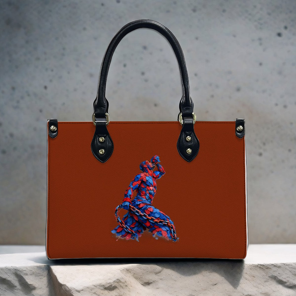 Brown handbag with black handle and blue and red embroidered design on a textured surface.